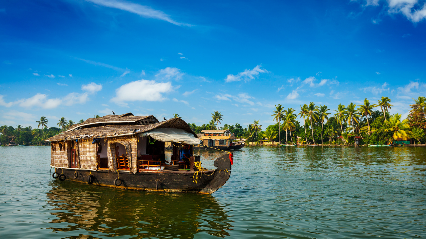 Traditional houseboat cruising through lush Goan backwaters surrounded by coconut palms