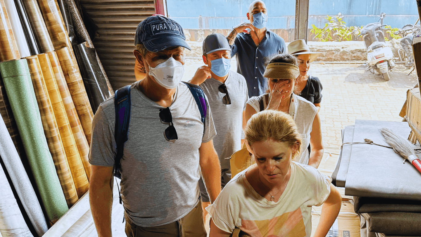 Travelers observing a small textile or material workshop during a guided tour in Mumbai
