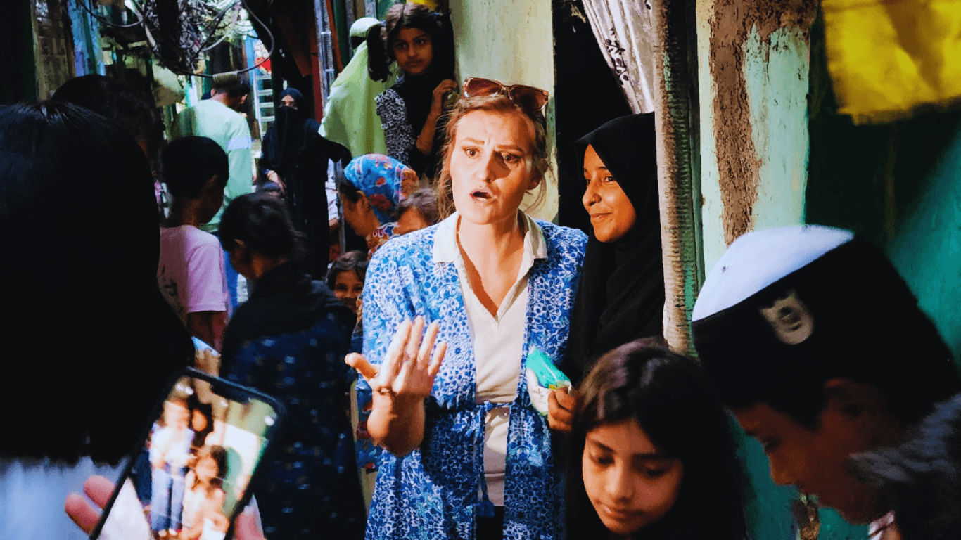 Woman speaking with local residents in a narrow neighborhood lane