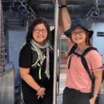 Two travelers smiling while standing inside a train carriage doorway