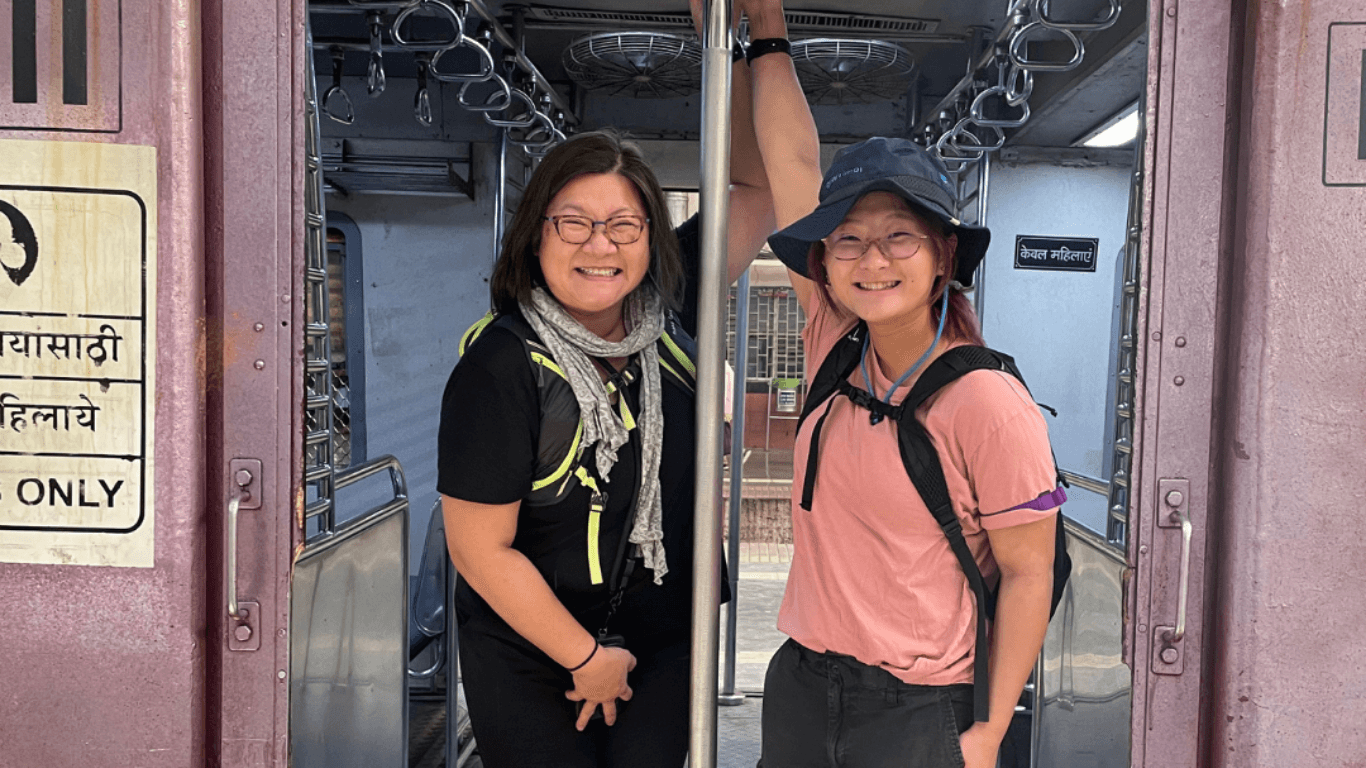 Two travelers smiling while standing inside a train carriage doorway