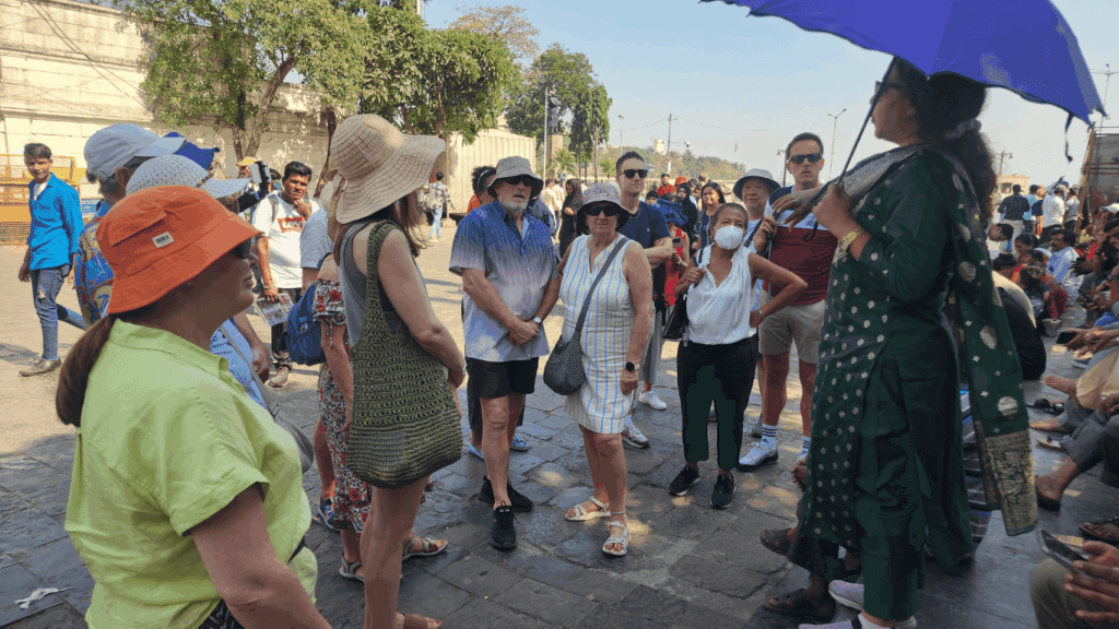 Tour guide explaining local history to a group of travelers during a guided walking tour in Mumbai.