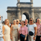 Independent shore excursions takes around a Group of international travelers posing together in front of the Gateway of India in Mumbai during a guided City Tour.
